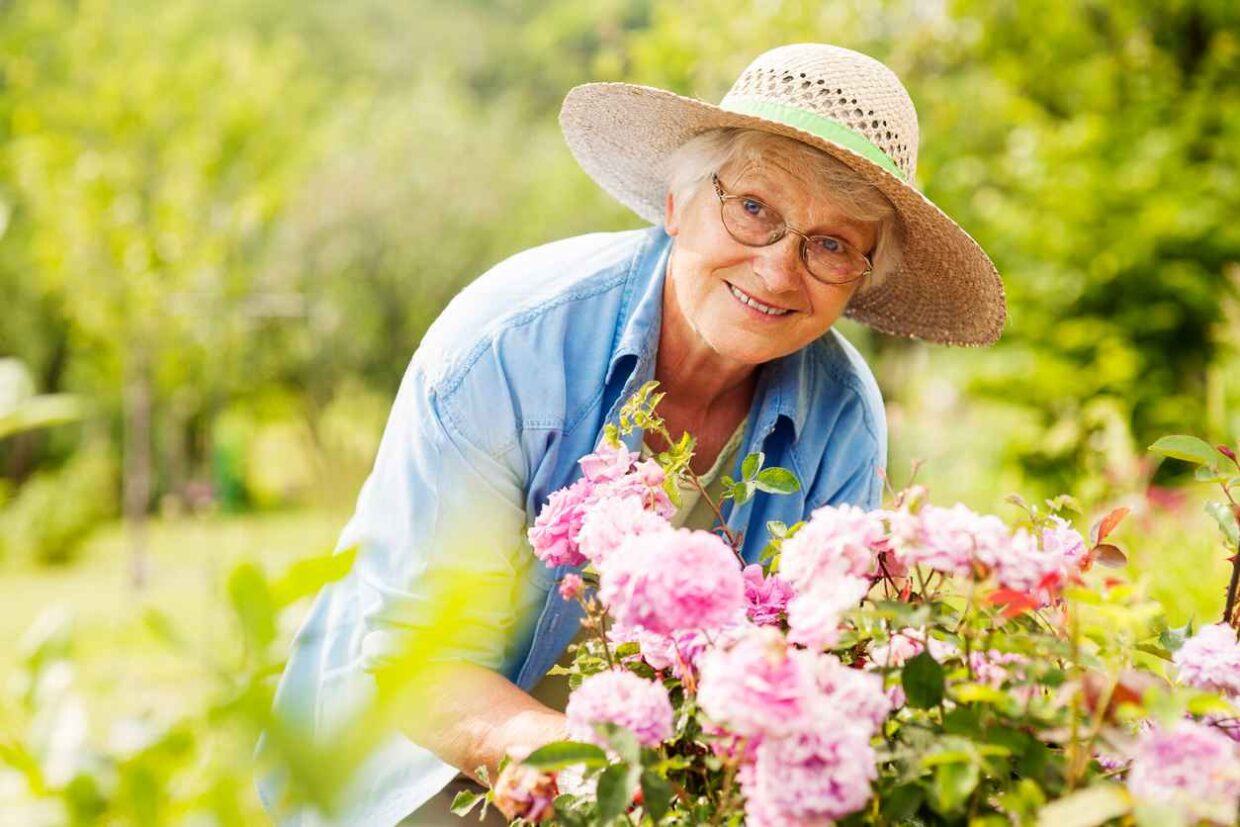 Senior woman with flowers in garden; The Benefits of the Outdoors for Seniors